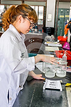 Female scientist examining boiled beaker chemical solution