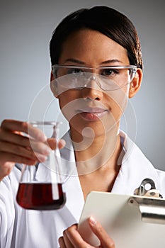 Female Scientist Examining Liquid In Flask