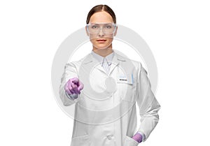 Female scientist in goggles pointing to camera