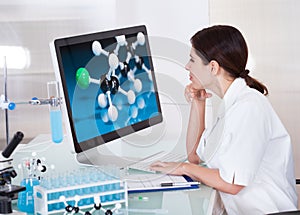 Female scientist looking on computer screen photo