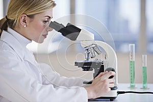 Female scientist looking through microscope