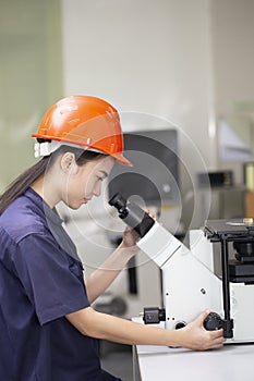 Female scientist looking in microscope in laboratory