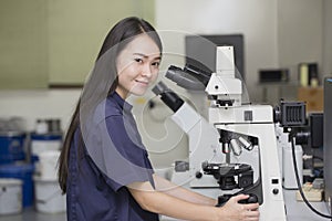 Female scientist looking in microscope in laboratory microscope