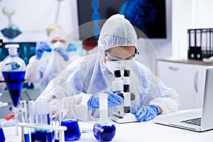 Female scientist looking through a microscope in research laboratory