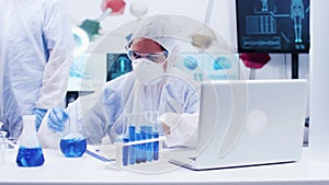 Female scientist looking at reactive blue solution and writing formula