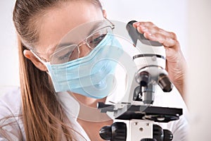Female scientist with microscope working in laboratory, closeup