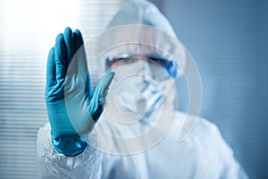Female scientist in protective hazmat suit with hand raised