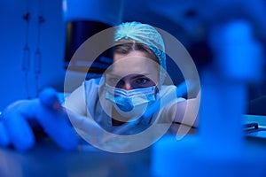 Female scientist in protective mask works with biomaterial in sterile laboratory