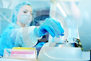 Female scientist in a protective medical mask and rubber gloves makes PCR DNA tests in a modern chemical and