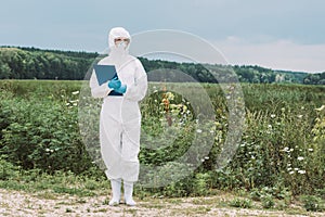 female scientist in protective suit and googles holding clipboard