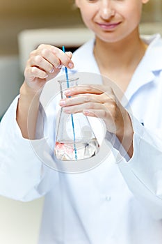 Female scientist shaking a liquid in an erlenmeyer