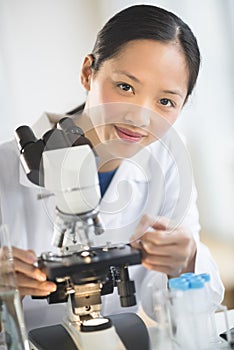 Female Scientist Smiling While Using Microscope