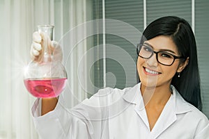 Female scientist with a test tube in a lab is researching a drug for the treatment of coronavirus.