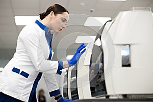 Female scientist using advia immunoassay system in laboratory