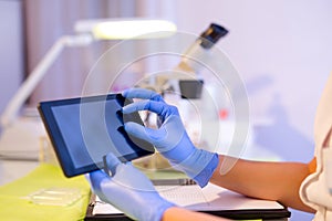 Female scientist using digital tablet in lab, close up.