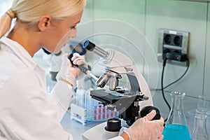 Female scientist working in modern lab. Doctor making microbiology research. Laboratory tools: microscope, test tubes