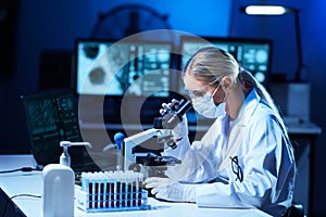 Female scientist working in modern lab. Doctor making microbiology research. Laboratory tools: microscope, test tubes