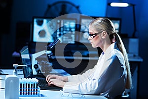 Female scientist working in modern lab. Doctor making microbiology research. Laboratory tools: microscope, test tubes