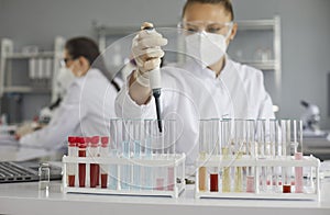 Female scientist working with pipette and glass tubes in pharma or biotech laboratory