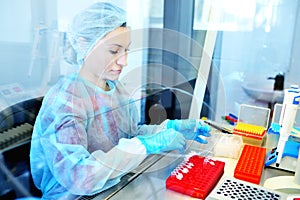 Female scientist works in a sterile genetic or bacteriological laboratory with a dispenser and reagents in a medical