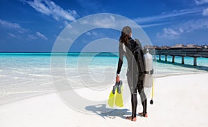 Female scuba diver with diving equipment on the beach