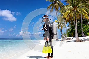 Female scuba diver stands on a tropical beach