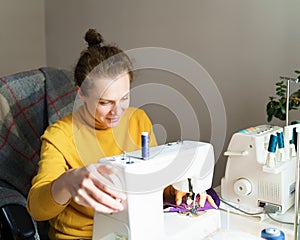 Female seamstress using sewing machine while working at home