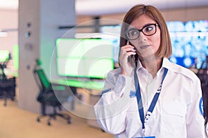 Female security guard operator talking on the phone, calling in the alarming event to the external team of field force agents