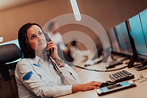 Female security guard operator talking on the phone while working at workstation with multiple displays Security guards