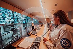 Female security guard operator talking on the phone while working at workstation with multiple displays Security guards