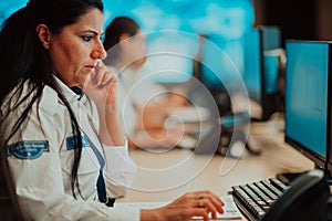 Female security guard operator talking on the phone while working at workstation with multiple displays Security guards