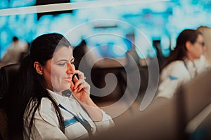 Female security guard operator talking on the phone while working at workstation with multiple displays Security guards