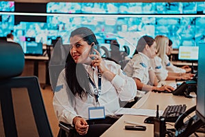 Female security guard operator talking on the phone while working at workstation with multiple displays Security guards