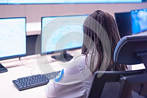 Female security guard working on computers while sitting in the main control room, CCTV surveillance