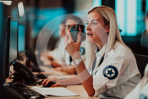 Female security operator holding portable radio in hand while working in a data system control room offices Technical