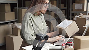 Female seller checking ecommerce parcel order in dropshipping warehouse.