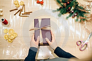 Female seller hands wrapping gift box, top view