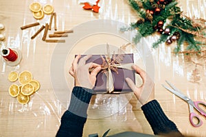 Female seller hands wrapping gift box, top view