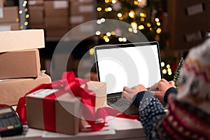 Female seller, internet shop small business owner wearing Santa hat checking online store dropshipping order on mock-up