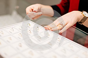 Female seller in a luxury jewelry store presents a ring.