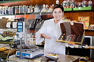 Female seller offering large box of chocolates