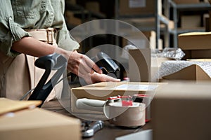 Female seller scanning ecommerce shipping box in dropshipping warehouse.