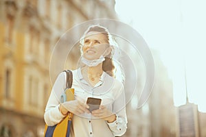 Female sending text message using smartphone outdoors in city