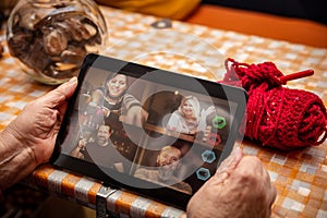 Female senior adult is holding a tablet in her hands, chatting or conference with family or friends