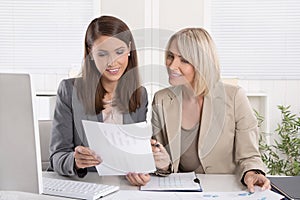 Female senior and junior managers sitting at desk working together in a business team.