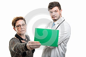 Female senior patient showing green board to male doctor