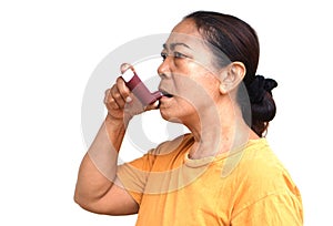 Female senior patient uses brown asthma inhaler for relief asthma.