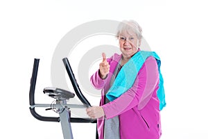 Female senior with thumb up train with fitness machine