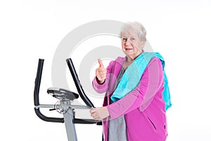 Female senior with thumb up train with fitness machine