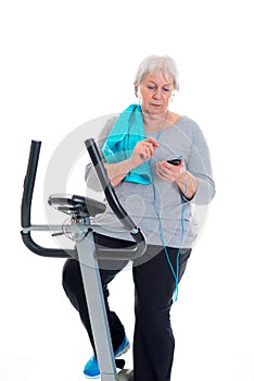 Female senior train with fitness machine and using phone